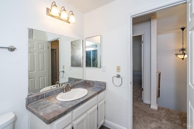 bathroom with baseboards, vanity, and toilet