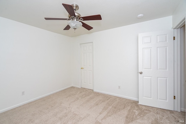 spare room with carpet floors, baseboards, and a ceiling fan