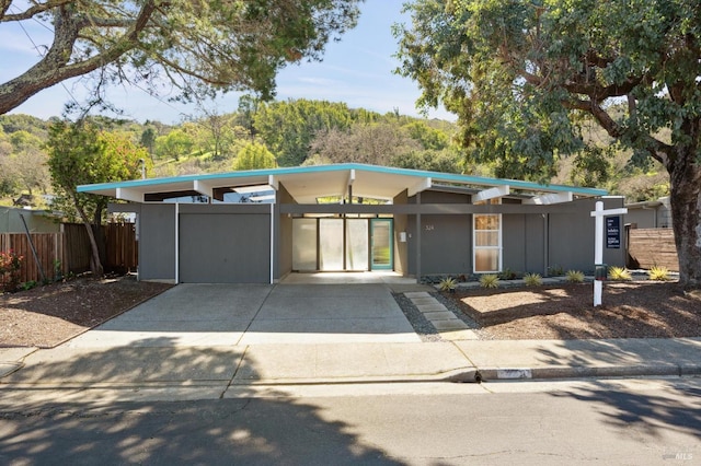 mid-century home with a carport, fence, and concrete driveway