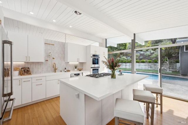 kitchen with a breakfast bar, appliances with stainless steel finishes, decorative backsplash, and light countertops