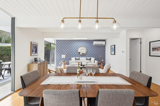 dining area with wooden ceiling, a wall unit AC, light wood-style flooring, an accent wall, and beam ceiling