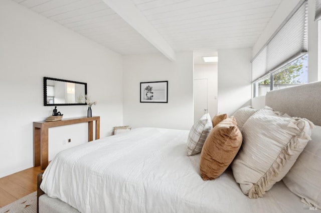 bedroom with beam ceiling and wood finished floors