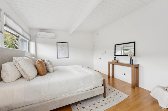 bedroom featuring a wall unit AC, beam ceiling, and wood finished floors