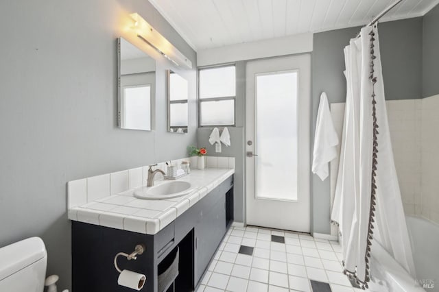 bathroom with toilet, tile patterned flooring, a wealth of natural light, and vanity