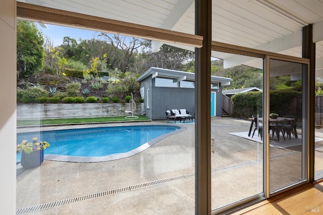 view of swimming pool featuring a fenced in pool, a patio, an outdoor structure, and fence