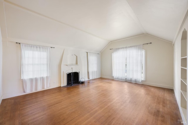 unfurnished living room with a fireplace, baseboards, vaulted ceiling, and wood finished floors