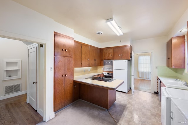 kitchen with stainless steel appliances, light countertops, visible vents, a sink, and a peninsula