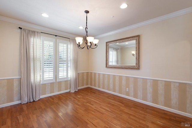 spare room with baseboards, ornamental molding, wood finished floors, and wallpapered walls