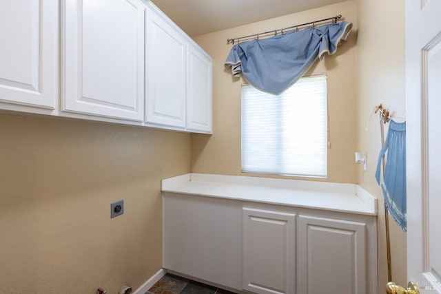 clothes washing area featuring cabinet space, electric dryer hookup, and baseboards