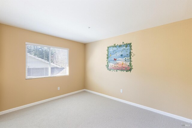 spare room with light carpet and baseboards