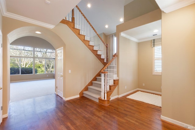 staircase with baseboards, visible vents, crown molding, and wood finished floors