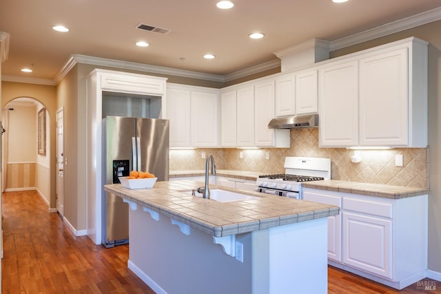 kitchen with white gas range, visible vents, a sink, stainless steel fridge, and under cabinet range hood