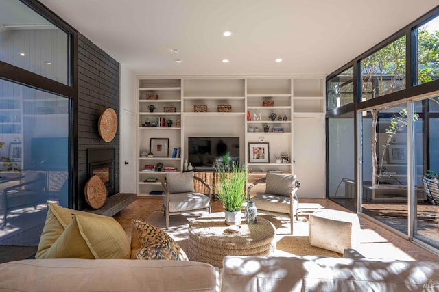 living area with a wall of windows, recessed lighting, a large fireplace, and built in shelves