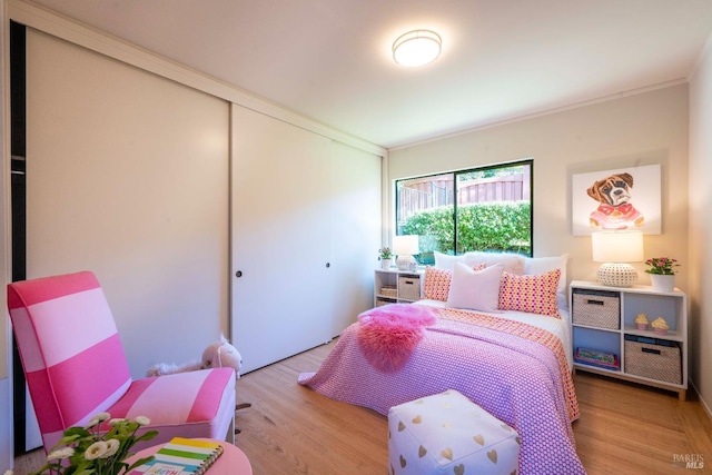 bedroom featuring light wood finished floors, a closet, and crown molding