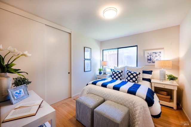 bedroom featuring light wood finished floors, baseboards, and a closet