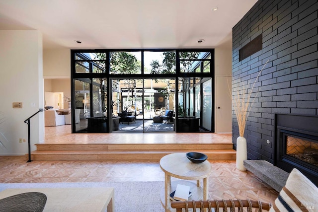 living area with a large fireplace, baseboards, and a wall of windows