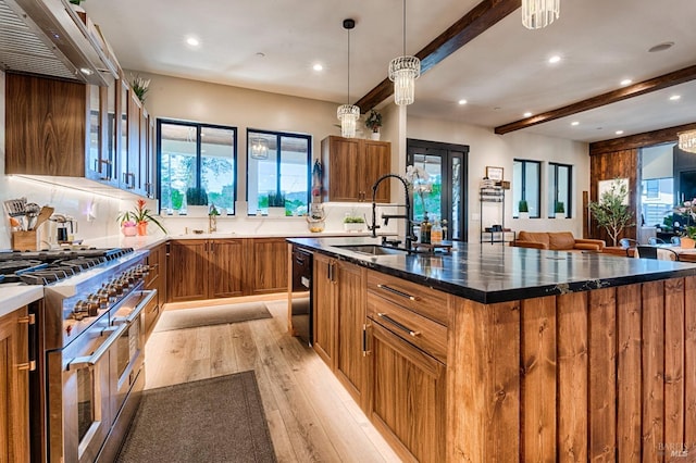 kitchen featuring a sink, double oven range, dishwasher, brown cabinetry, and a center island with sink