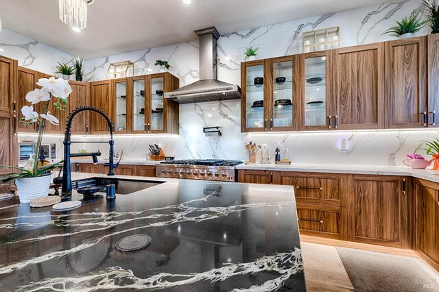 kitchen featuring brown cabinets, glass insert cabinets, ventilation hood, and stove