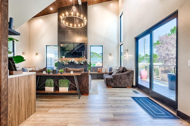 living area featuring wood finished floors, a towering ceiling, and an inviting chandelier