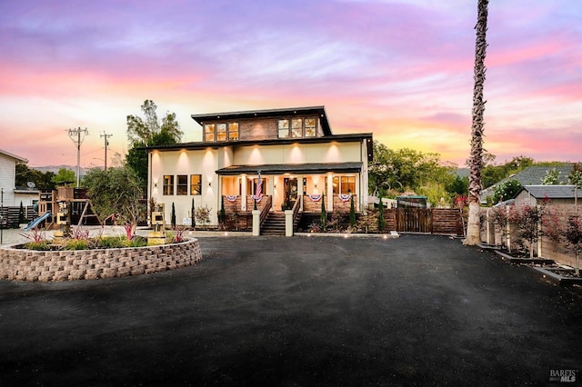 view of front of house with a playground, fence, and stucco siding