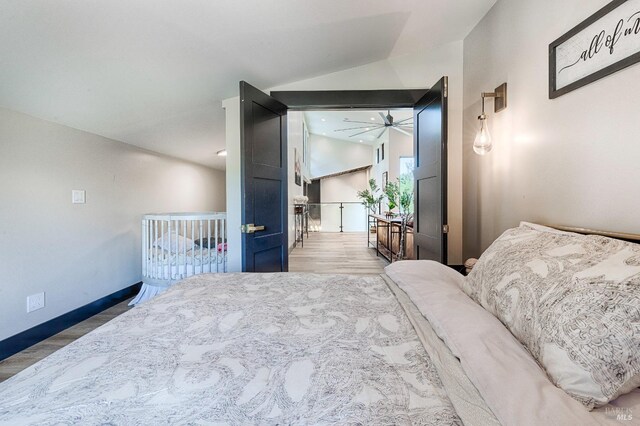 bedroom with vaulted ceiling, baseboards, and wood finished floors