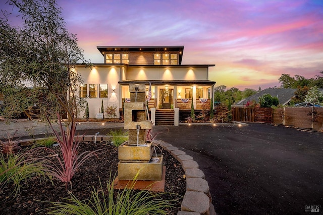 back of house featuring covered porch, fence, a balcony, and stucco siding