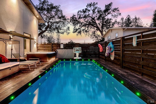 view of pool with a hot tub, a fenced in pool, a fenced backyard, and a wooden deck