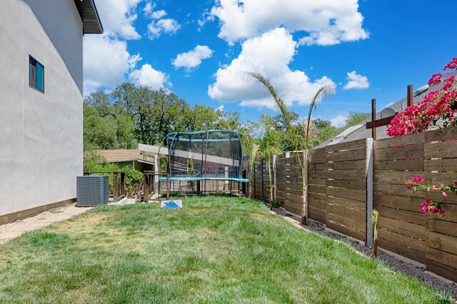 view of yard with a trampoline, cooling unit, and a fenced backyard