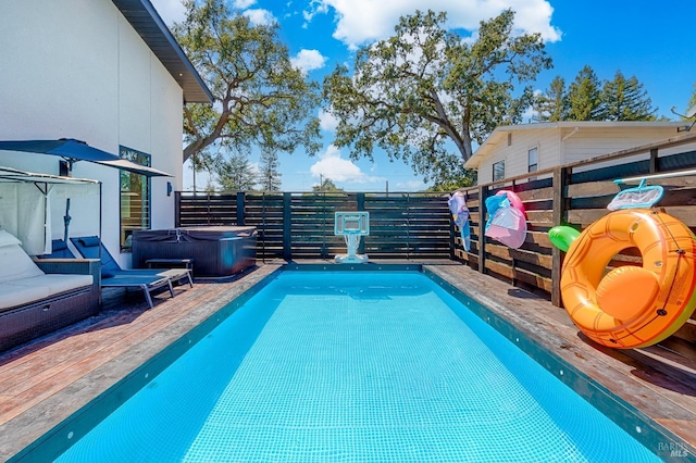 view of swimming pool featuring a wooden deck, a fenced in pool, and a hot tub