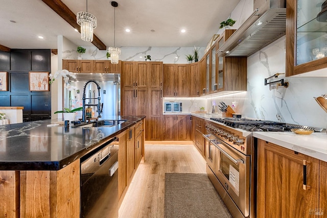 kitchen with a center island with sink, brown cabinets, high end appliances, glass insert cabinets, and custom range hood