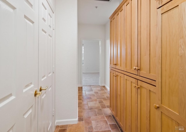 hallway with stone finish flooring, visible vents, and baseboards