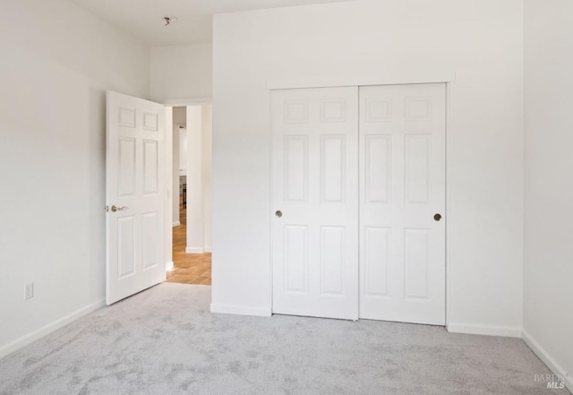 unfurnished bedroom with a closet, baseboards, and carpet flooring