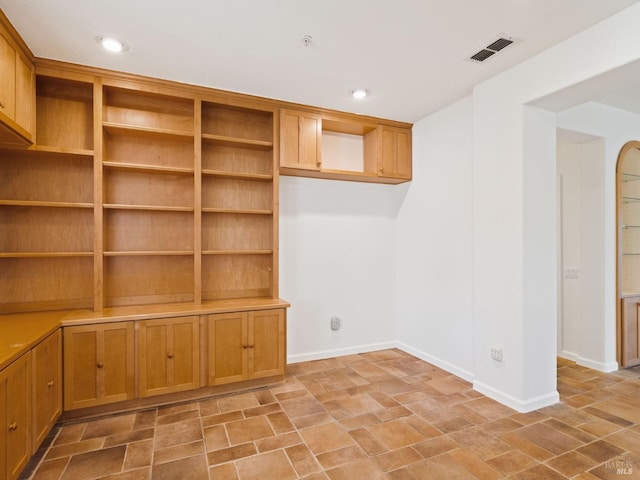 empty room featuring recessed lighting, stone finish flooring, visible vents, and baseboards