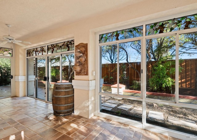 doorway with stone tile floors, ceiling fan, and a textured ceiling