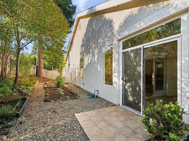 view of side of home with a patio, fence, and stucco siding