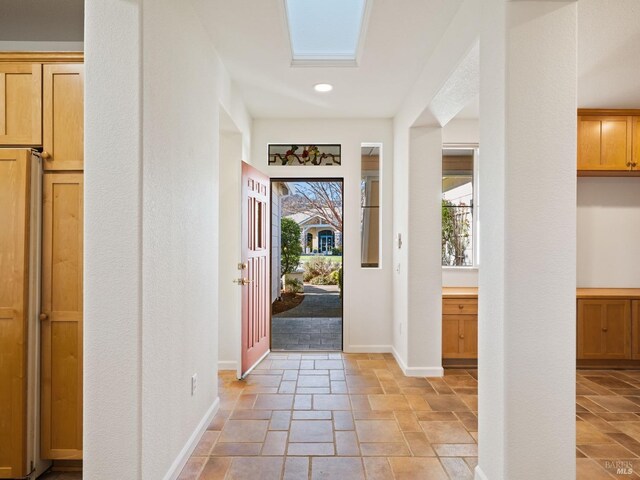 entryway with a skylight, stone tile flooring, and baseboards