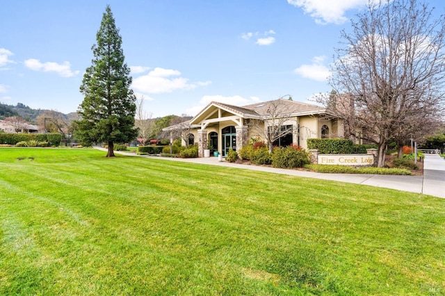 view of front of home featuring stone siding, a front lawn, and concrete driveway