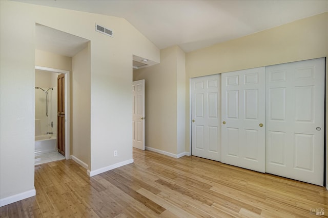 unfurnished bedroom with lofted ceiling, light wood-style flooring, visible vents, and baseboards