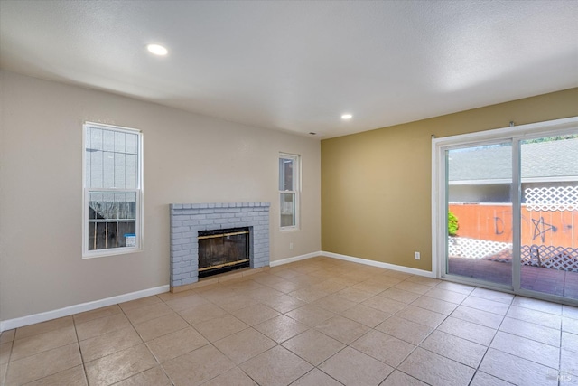 unfurnished living room with a brick fireplace, baseboards, and light tile patterned flooring