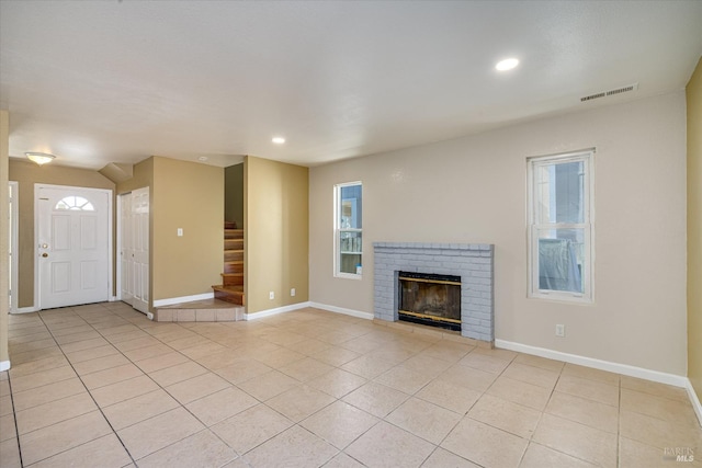 unfurnished living room with baseboards, visible vents, stairway, a fireplace, and light tile patterned flooring