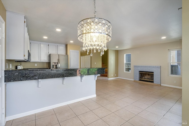 kitchen with light tile patterned floors, white cabinetry, a kitchen breakfast bar, stainless steel fridge with ice dispenser, and decorative light fixtures