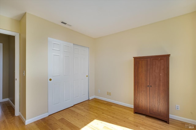 unfurnished bedroom with light wood finished floors, visible vents, and baseboards