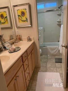 bathroom featuring tile patterned flooring, tub / shower combination, toilet, and double vanity