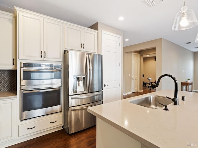 kitchen featuring stainless steel appliances, visible vents, decorative backsplash, dark wood-type flooring, and a sink