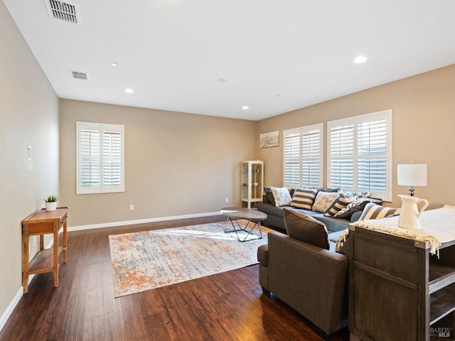 living room featuring dark wood finished floors, visible vents, and baseboards