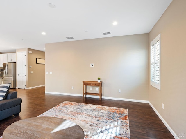 living area with baseboards, visible vents, dark wood finished floors, and recessed lighting