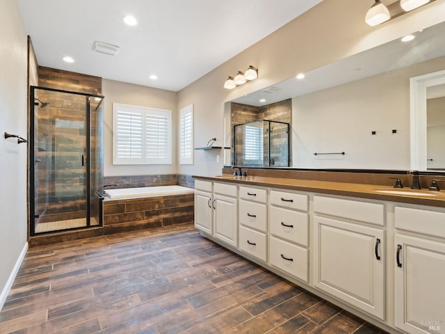 bathroom featuring a garden tub, wood finished floors, a sink, and a shower stall