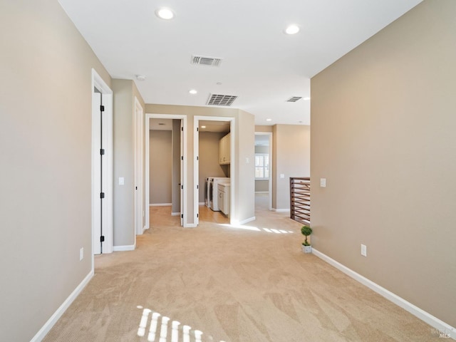 empty room with baseboards, visible vents, and light colored carpet