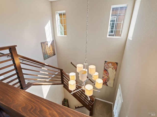 stairs with a chandelier, carpet floors, and a high ceiling