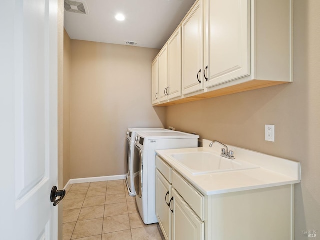 clothes washing area with cabinet space, light tile patterned floors, visible vents, washing machine and dryer, and a sink